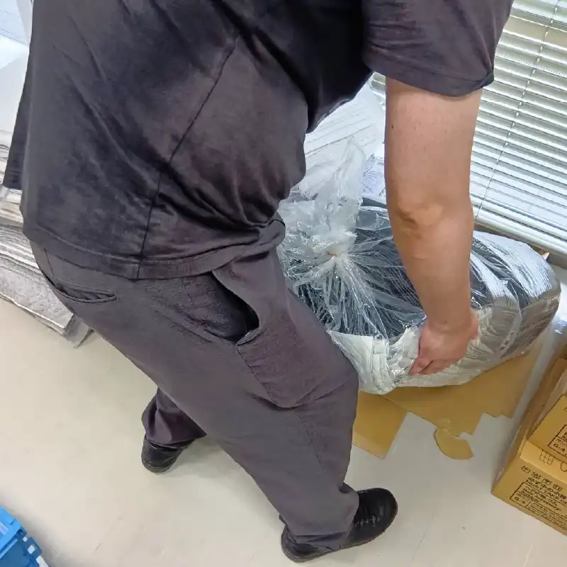 ビニールで丁寧に梱包された製品を慎重に持ち上げる利用者さんの様子