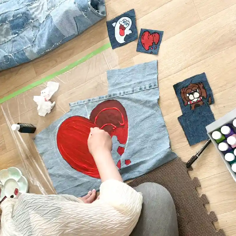 赤い絵の具で大胆なデザインを施すリメイクデニムの制作過程