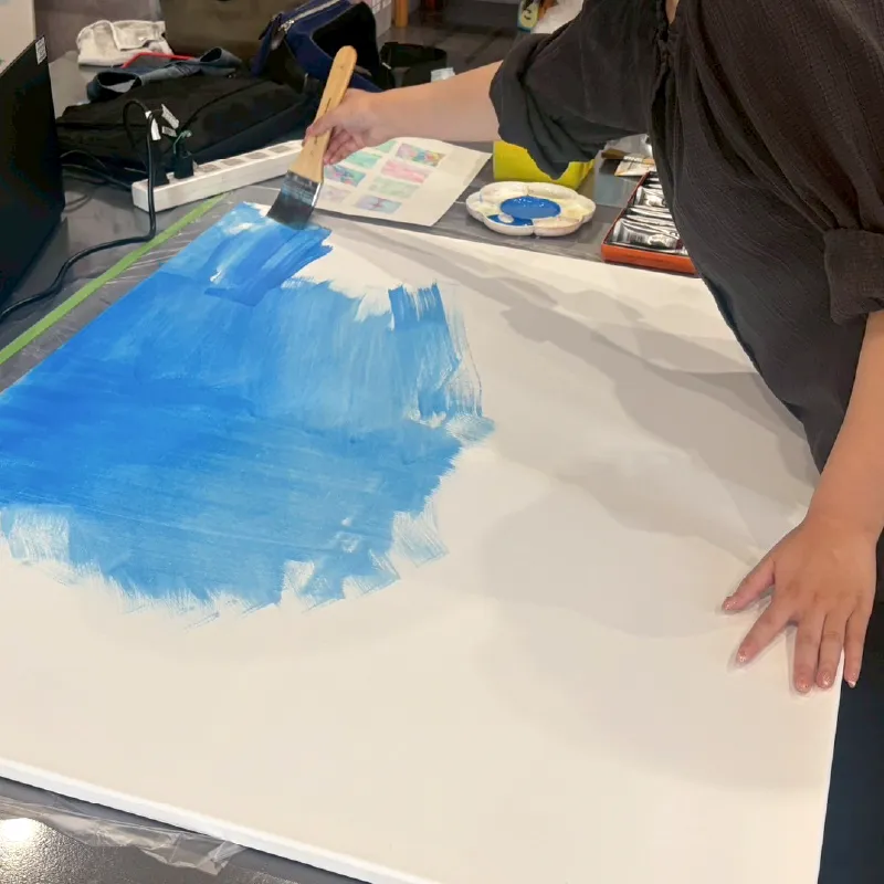 ペイティング制作を始める利用者さんの様子。キャンバスに色を広げています。