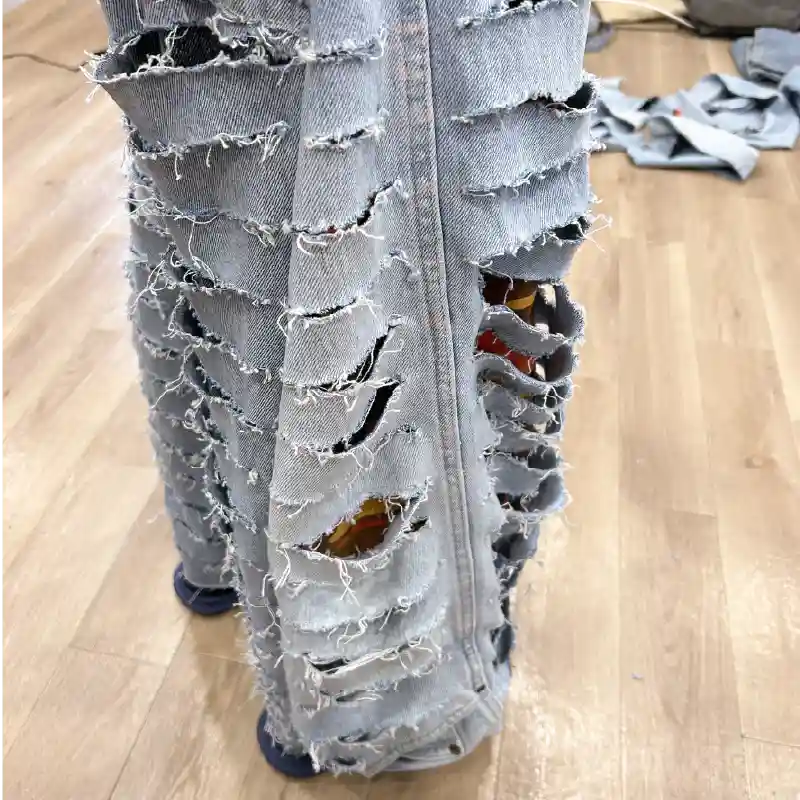 リメイクデニムのクラッシュ部分の拡大。裂け目から赤いカモフラージュ柄の裏地が見えている