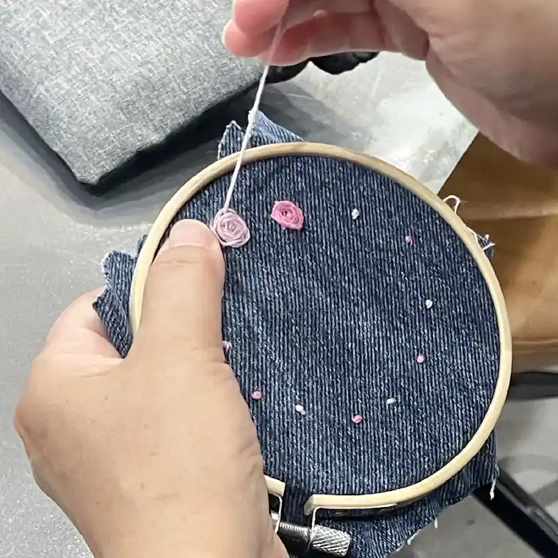 デニムに濃淡ピンクの糸で刺繍をしている様子。