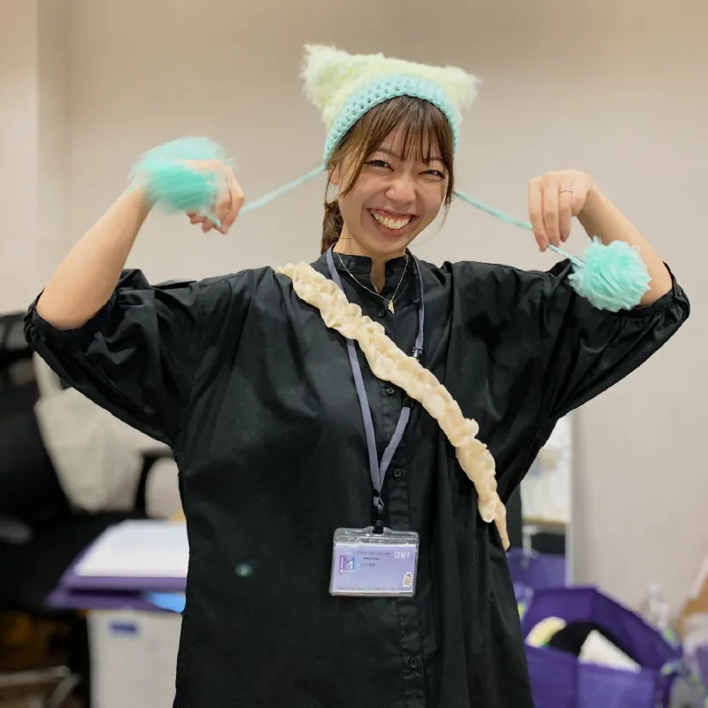 利用者さんが作ったパステルカラーのニット帽を被ってノリノリの職員