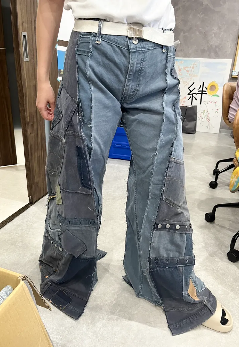 複数のデニム生地を大胆にパッチワークで繋ぎ合わせた、ワイドシルエットのリメイクデニムパンツを試着している女性職員の正面全体像。
