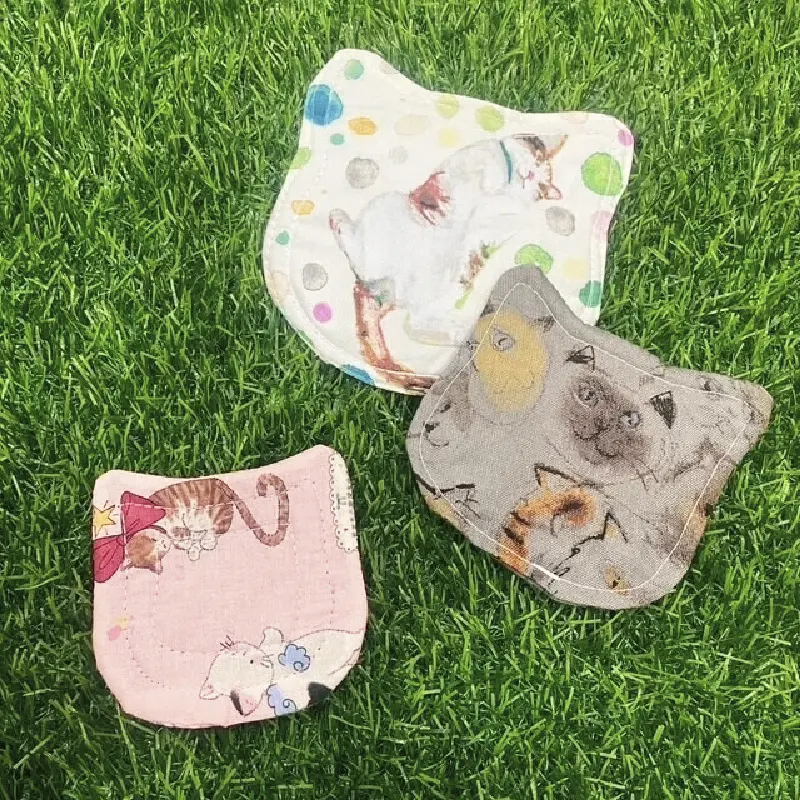 猫の顔の形をした布製ハンドタオル。カラフルな布地とイラストが特徴で、持ち歩くだけで気分が上がる。
