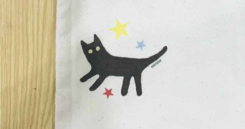完成した猫デザインのトートバッグが正面に置かれ、クリエイティブなものづくりの過程を象徴するシーン