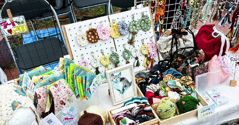 大阪の就労継続支援A型事業所の利用者さんが制作したものづくり作品と展示ブースの様子 説明: 中央区民まつりで出店したA型事業所のブース。利用者さんが制作したコースターやポーチなど、多彩な作品が整然と並ぶ光景。