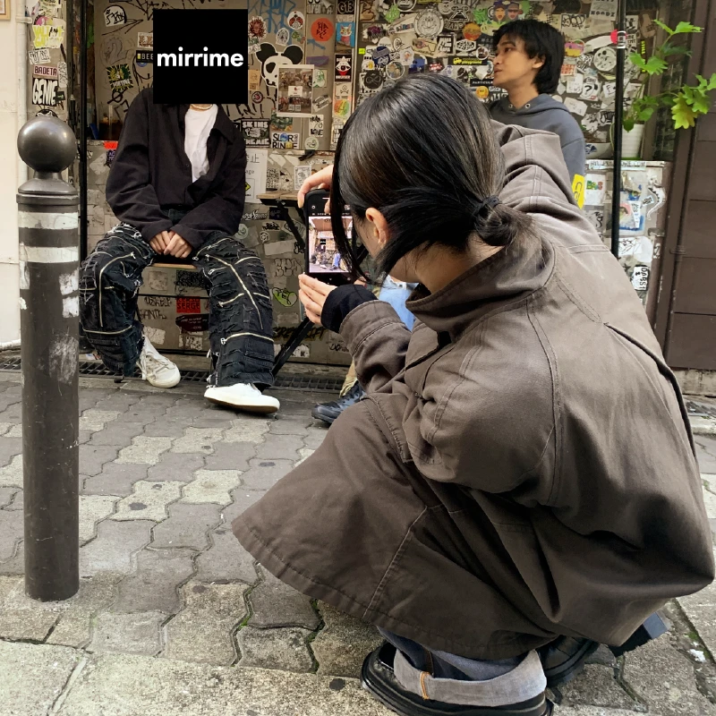 ステッカーだらけの壁でリメイクデニムを撮影する利用者さん