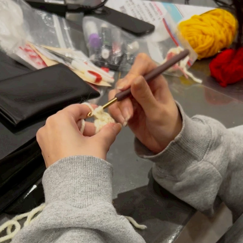 毛糸を手に取り、ぬいぐるみの服を編み始める様子