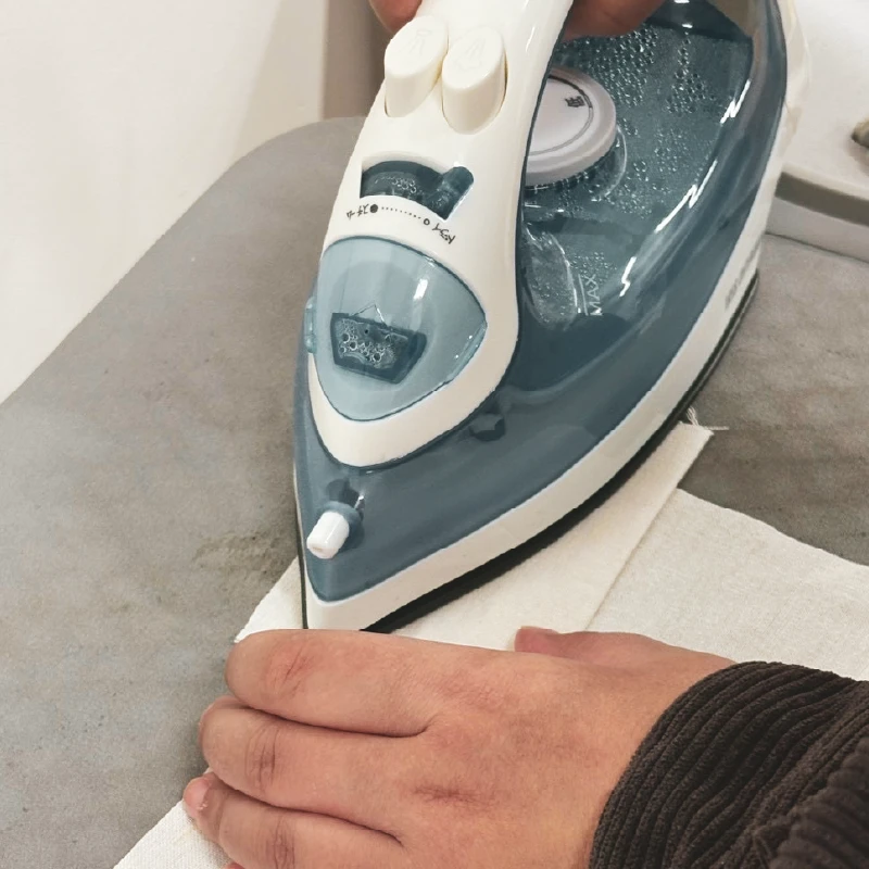 巾着の形を整えるために布へ折り目をつけている様子