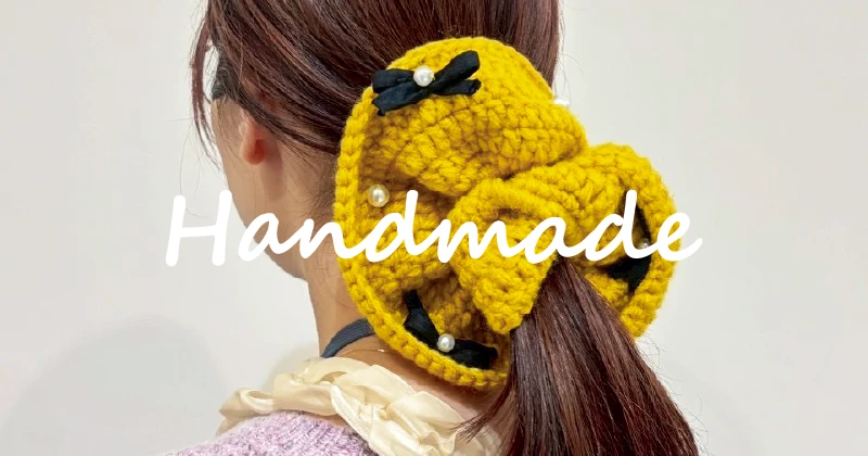 編み物で制作したクリスマスカラーのシュシュを手に持った様子