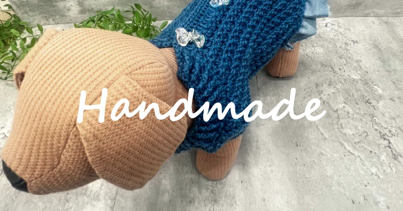 利用者さんが編んだ藍色の子犬用ニット服を手に持っている様子